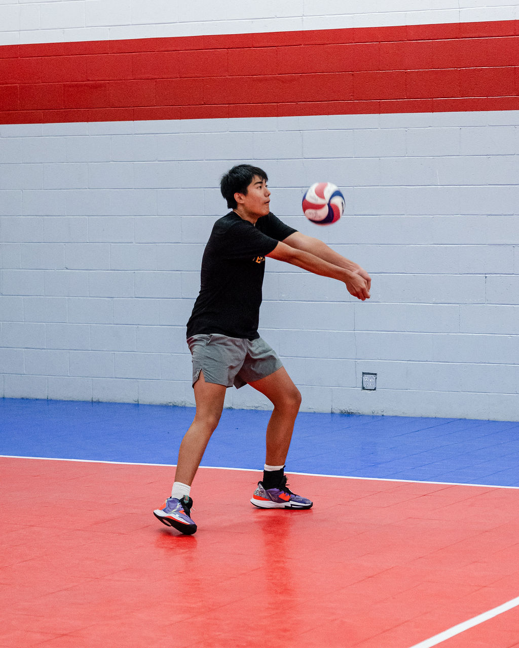 The key is to find the stance that allows you to quickly move your arms in a running motion to reach the ball before presenting your platform to pass it. The goal is to minimize the time it takes to transition from the ready position to actual ball contact.